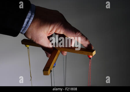 Businessman pulling puppet strings Stock Photo