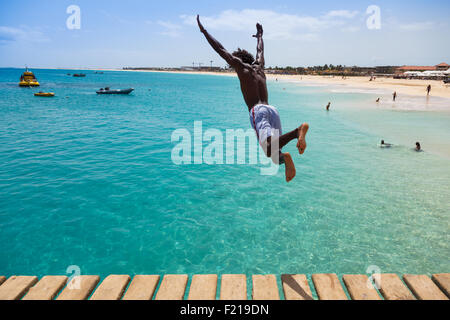 Teenage Cape verdean boy jumping on the turquoise  water of Santa Maria beach in Sal Cape Verde - Cabo Verde Stock Photo