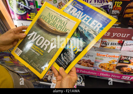 A reader with copies of National Geographic and Nat Geo Traveler at a newsstand in New York on Wednesday, September 9, 2015. In a partnership with 21st Century Fox National Geographic magazine will change to for-profit status with Fox paying $725 million for a 73 percent stake to the non-profit National Geographic Society. The sale includes the cable channel and the society's other media assets. (© Richard B. Levine) Stock Photo