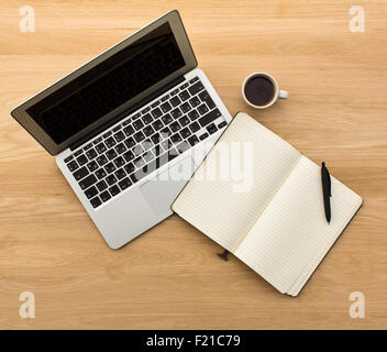 Laptop, opened a notebook, pen and Cup of coffee lying on a wooden table top view. Stock Photo