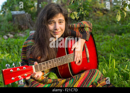 Young girl playing acoustic guitar outdoors. Stock Photo