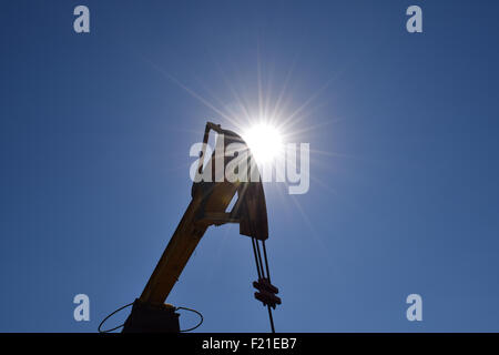 The pumping unit as the oil pump installed on a well. Equipment of oil fields. Stock Photo