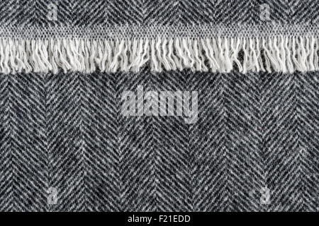 Herringbone wool tweed fabric background with closeup on textile texture and overlapping fringe edge Stock Photo