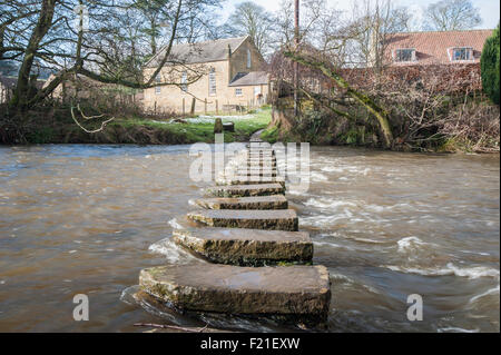 Stepping stones across a small river in english rural village countryside scene. Stock Photo