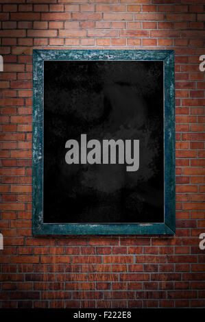A blank blackboard under a spotlight and hanging on a brick wall. Stock Photo