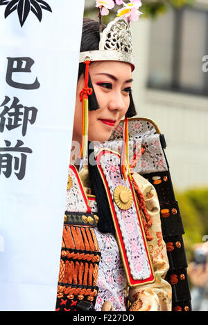 Genji festival parade in Tada, Japan. Close up of young woman on horseback, dressed in samurai armour with small Heian era crown on head, smiling. Stock Photo