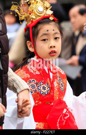 Genji Tada shrine festival. Parade of children dressed in Heian period costume. Young girl, 6-8 year old, with gold crown, white robe and red jacket. Stock Photo