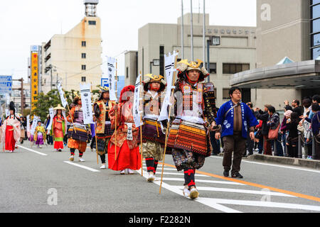 Genji festival parade in Japan. Japanese men dressed as samurai in full armour, marching along the main street, all carrying banners. Stock Photo