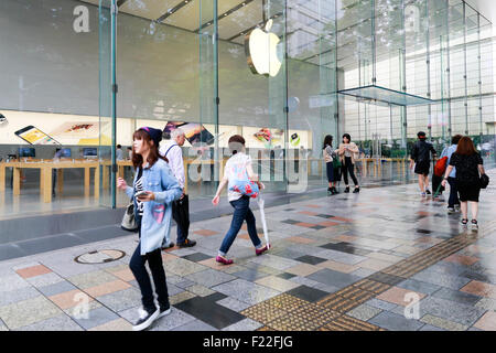 Pedestrians walk past the Apple Store in Omotesando on September 10, 2015, Tokyo, Japan. Even after Apple CEO Tim Cook announced their new products iPad Pro, iPhone 6s, iPhone 6s Plus and Apple TV on September 9, 2015, hardcore Japanese fans were nowhere to be seen outside the principal stores in Ginza and Omotesando. This could be because of heavy rain that hit Japan this week caused by typhoon Etau, or perhaps Apple fans are now less excited by this clockwork new release cycle. In Australia the media already reported that the first Apple fan had set up a tent in front of the store in Sydney. Stock Photo