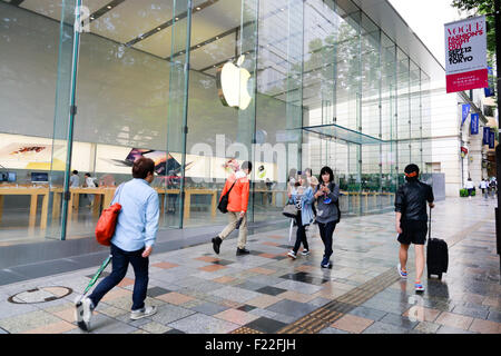 Pedestrians walk past the Apple Store in Omotesando on September 10, 2015, Tokyo, Japan. Even after Apple CEO Tim Cook announced their new products iPad Pro, iPhone 6s, iPhone 6s Plus and Apple TV on September 9, 2015, hardcore Japanese fans were nowhere to be seen outside the principal stores in Ginza and Omotesando. This could be because of heavy rain that hit Japan this week caused by typhoon Etau, or perhaps Apple fans are now less excited by this clockwork new release cycle. In Australia the media already reported that the first Apple fan had set up a tent in front of the store in Sydney. Stock Photo