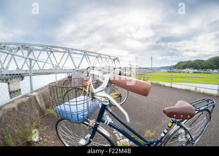 A close up fisheye shot of a bicycle with a bridge in the background. Stock Photo