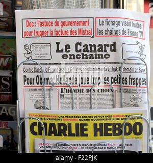 Paris, France. 10th Sep, 2015. An edition of French satire magazine 'Le Canard enchaine' (top) is on display above an edition of the magazine 'Charlie Hebdo' at a newspaper stand in Paris, France, 10 September 2015. Le Canard enchaine is celebrating its 100th anniversary this year. The magazine is renown in France for its humoristic investigative journalism. Photo: Winnie Bennedsen/dpa/Alamy Live News Stock Photo