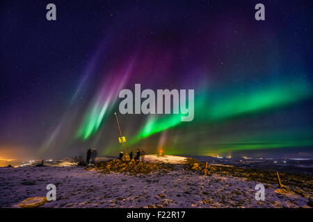 People enjoying the Aurora Borealis or Northern lights on Mt. Ulfarsfell, near Reykjavik,  Iceland. The Hellisheidi Power Plant Stock Photo