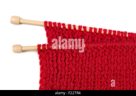 Red knitted wool fabric on wooden spokes. Isolate on white. Stock Photo