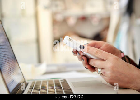 A woman using a laptop and a smart phone, making calls, running a business. Stock Photo