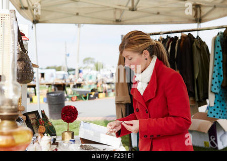 A mature woman bargain hunter browsing through vintage jewellery items at a clothing stall at a flea market. Stock Photo
