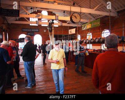 Chappel, Essex, UK. 9th September 2015. Bar in the Goods Shed at the Chappel Beer Festival, held at the East Anglian Railway Museum, Chappel & Wakes Colne Station, Chappel, Essex, UK. Features bar staff,  drinkers and racks of real ale beer barrels. Credit:  archaeo Images/Alamy Live News Stock Photo