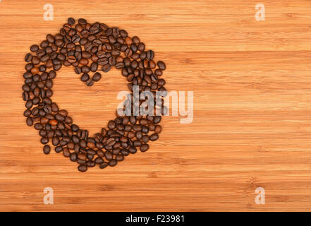 Heart shaped coffee beans round frame of Roasted Arabica coffee espresso beans over wooden bamboo board background Stock Photo
