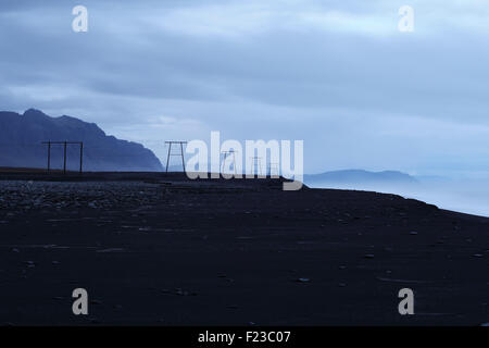 Pylons carry wires along the south-east coast of Iceland. Stock Photo