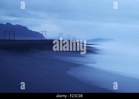 Pylons carry wires along the south-east coast of Iceland. Stock Photo