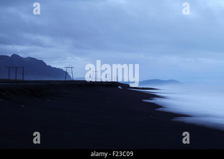 Pylons carry wires along the south-east coast of Iceland. Stock Photo