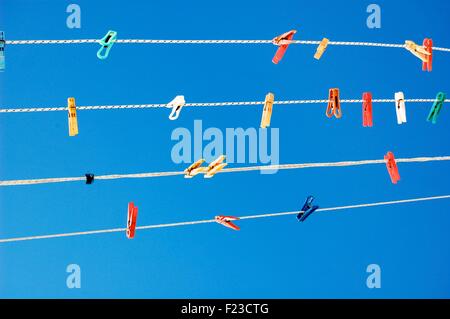 Multicolored pegs on washing lines against a bright blue sky Stock Photo