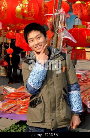 Pengzhou Township, China:  Smiling teenaged Chinese youth selling Chinese New Year decorations at a roadside booth Stock Photo