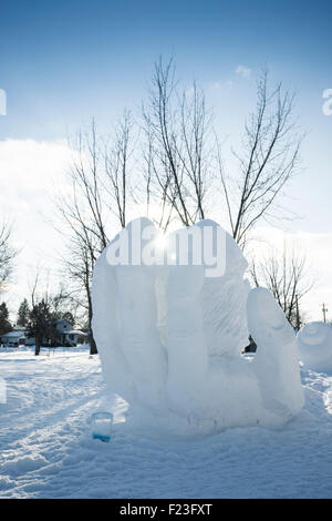 Snow sculpture of giant curved hand with sun flare at the winter tracks festival in Ely, MN, USA Stock Photo