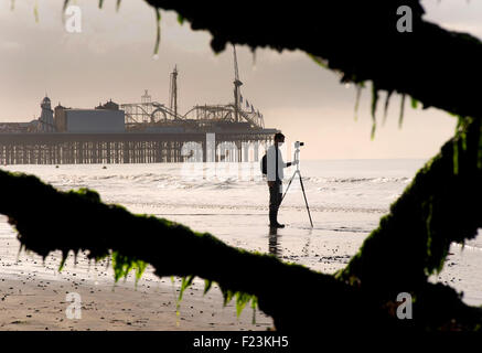 Silhouette of the Palace Pier now called Brighton Pier and photographer, Brighton. Low tide. East Sussex, England Stock Photo