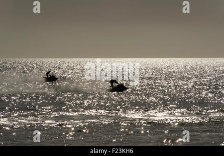 Jet Skiing off Brighton beach. Silhouettes in a glimmering sea Stock Photo