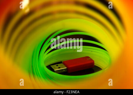 USB stick and Rainbow coloured slinky toy made of a plastic wire spiral coil which enables flexibility and mobility Stock Photo