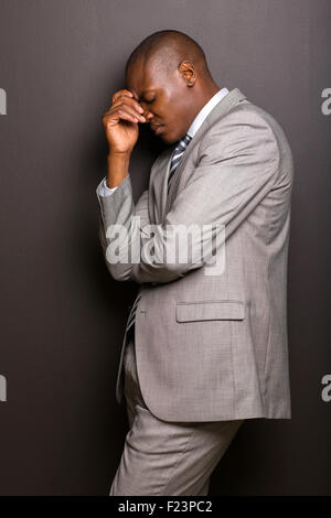 stressed African American man standing against black background Stock Photo