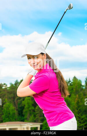 girl on the golf course with a golf club ready to hit the ball Stock Photo