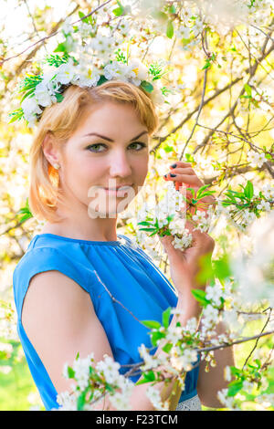 portrait of a girl with a wreath on his head in the branches of cherries Stock Photo