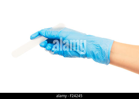 Close up of female doctor's hand in blue sterilized surgical glove with white plastic medical spatula against white background Stock Photo