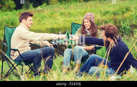 group of smiling tourists drinking beer in camping Stock Photo
