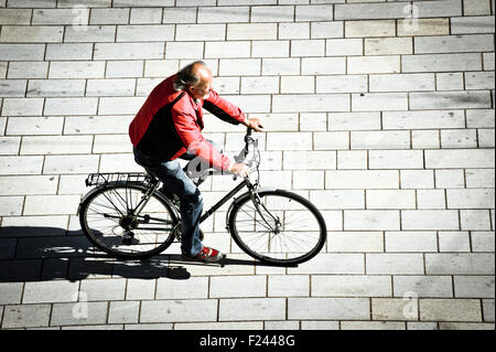 man in red jacket riding a bicycle, view form above Stock Photo