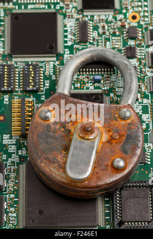 Old rusty locked padlock on computer mainboard - information or data security concept Stock Photo