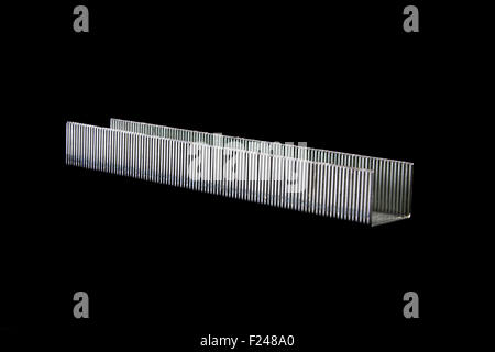 A stack of silver colored staples or stapler pins, isolated on black studio background. Stock Photo