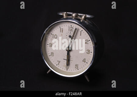A vintage alarm clock with a white dial, on black studio background. Stock Photo