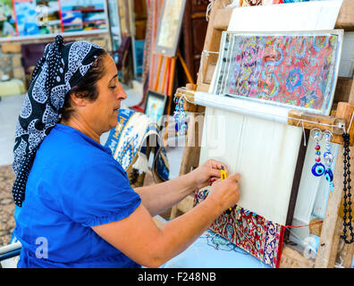 Side, Turkey - May 24, 2015: An unidentified  woman weaves a carpet by hand Stock Photo