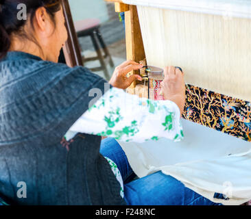 Side, Turkey - May 24, 2015: An unidentified woman weaves a carpet by hand. Focus on the fabric. Stock Photo