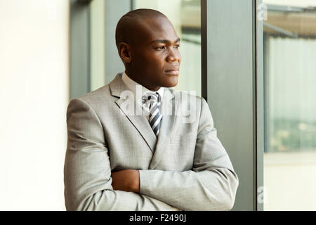 thoughtful young African businessman with arms crossed Stock Photo
