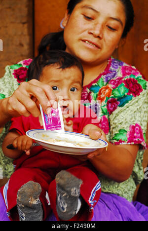 Guatemala, San Bartolo, mother giving complementary food chispitas to baby (Osber danilo sontay Ramirez 11 months, Candelaria Sandiega Ramirez Ramires 23 years) Stock Photo