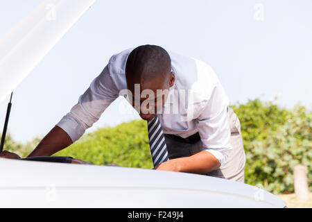 African businessman repairing a broken car by the road Stock Photo