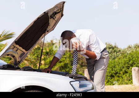 young man with broken down car with bonnet open calling for help Stock Photo