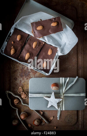 Gingerbead with rich chocolate coating and almonds in open silver box and a box wrapped with ribbon. Top view Stock Photo
