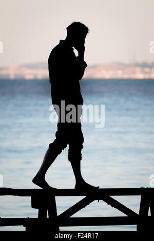 Man talking on cell phone next to water Stock Photo