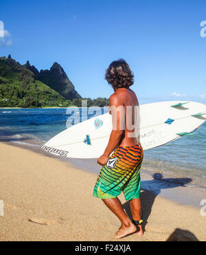 Surfer at Tunnels Beach on Kauai looks at Mt. Makana, called Bali Hai Stock Photo