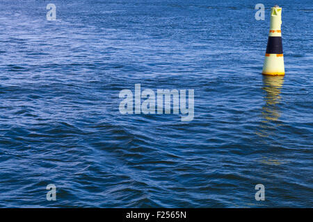 Yellow modern navigation buoy with black stripe floating on a sea water Stock Photo